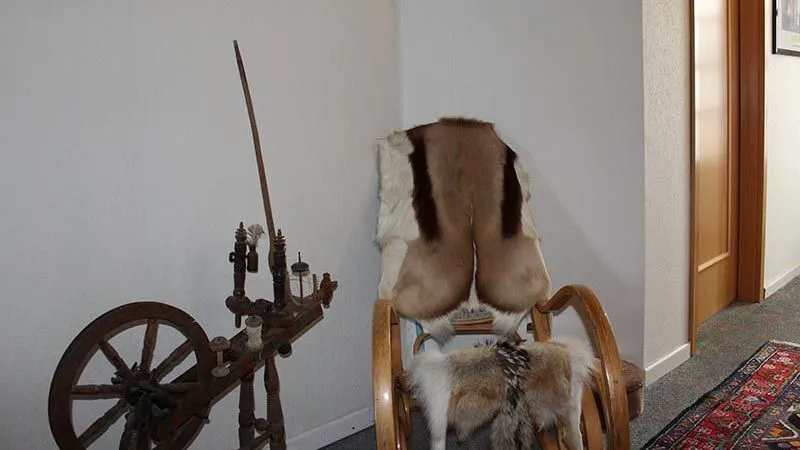 Altes Spinnrad und Sessel mit Fell im Flur